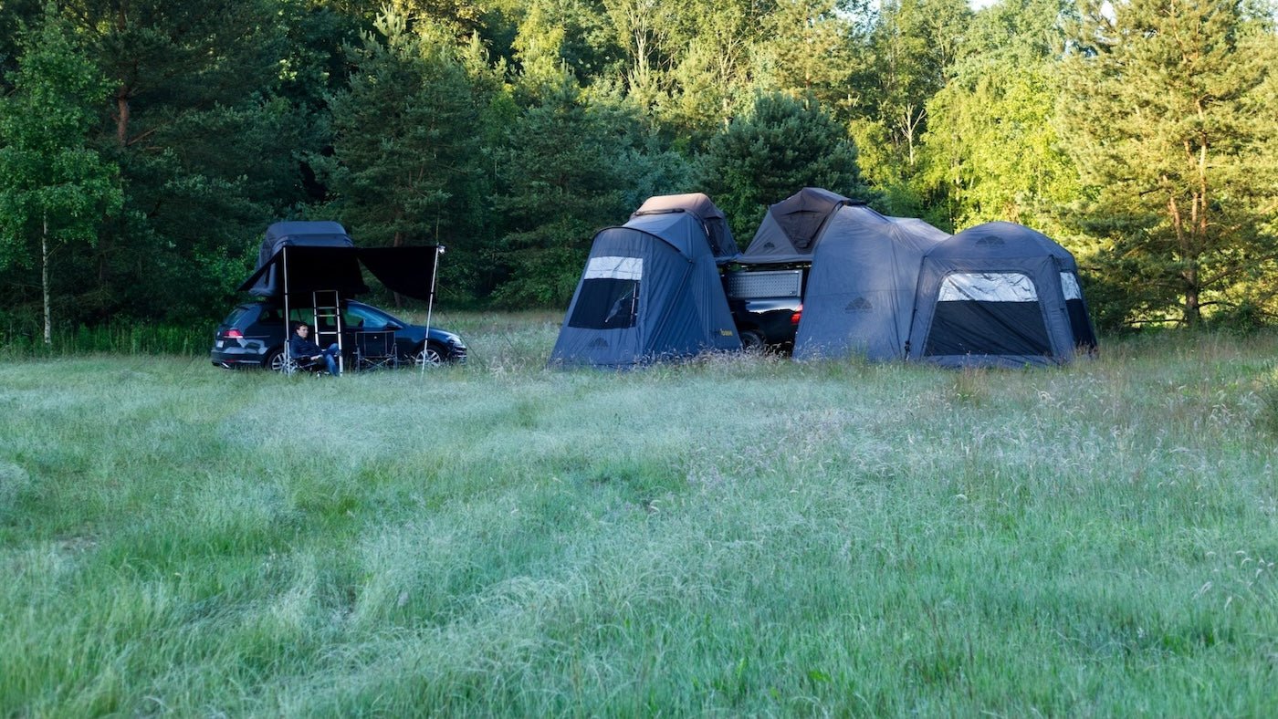 Camping-Szene mit Dachzelten und Zubehör in natürlicher Umgebung, dunkelgraue Farbtöne, Abenteuer- und Reiselifestyle.