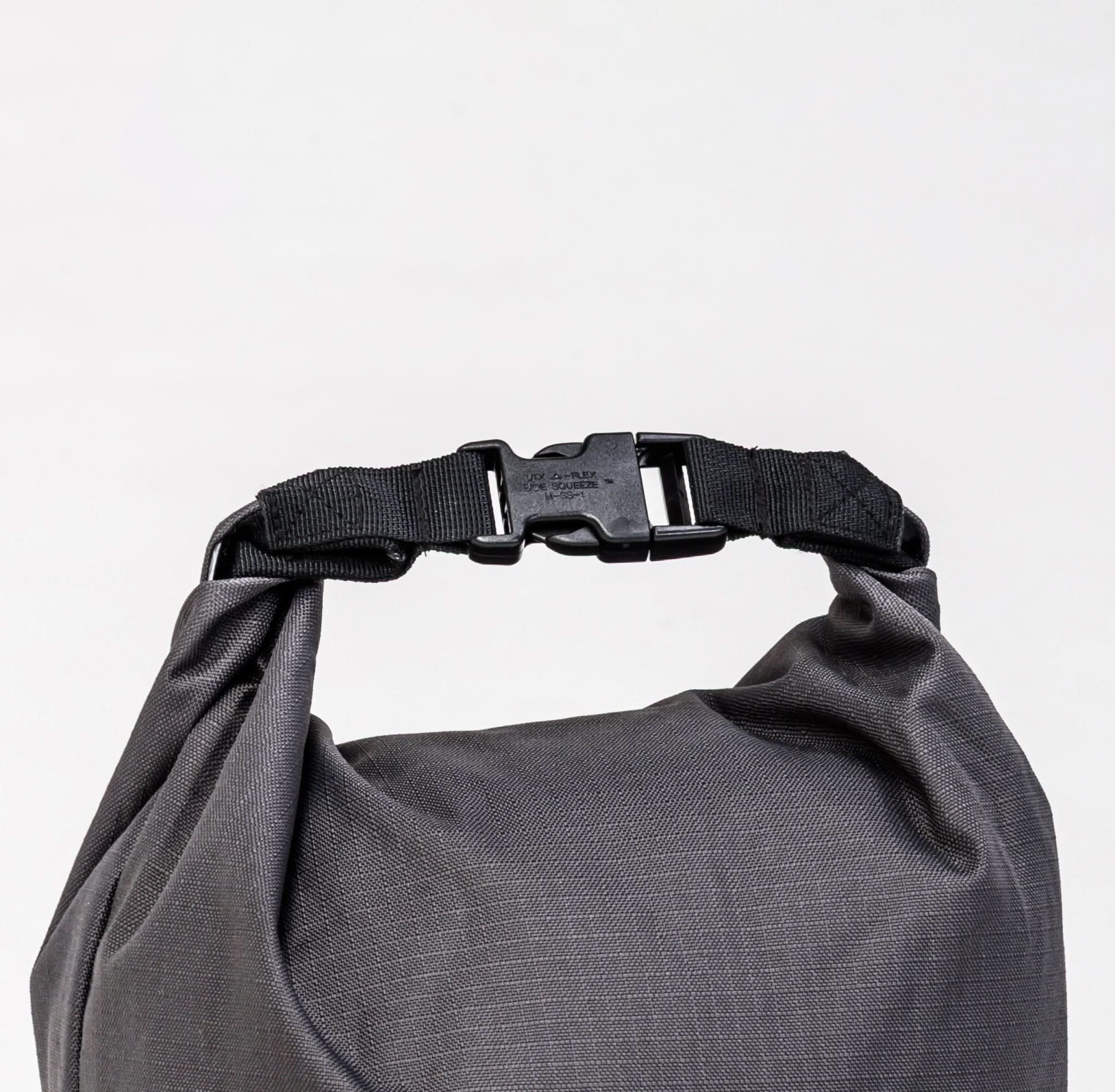 Nahaufnahme eines grauen Seesacks mit schwarzem Gurtband und UTX FLEX Side Squeeze-Schnalle vor einem weißen Hintergrund.