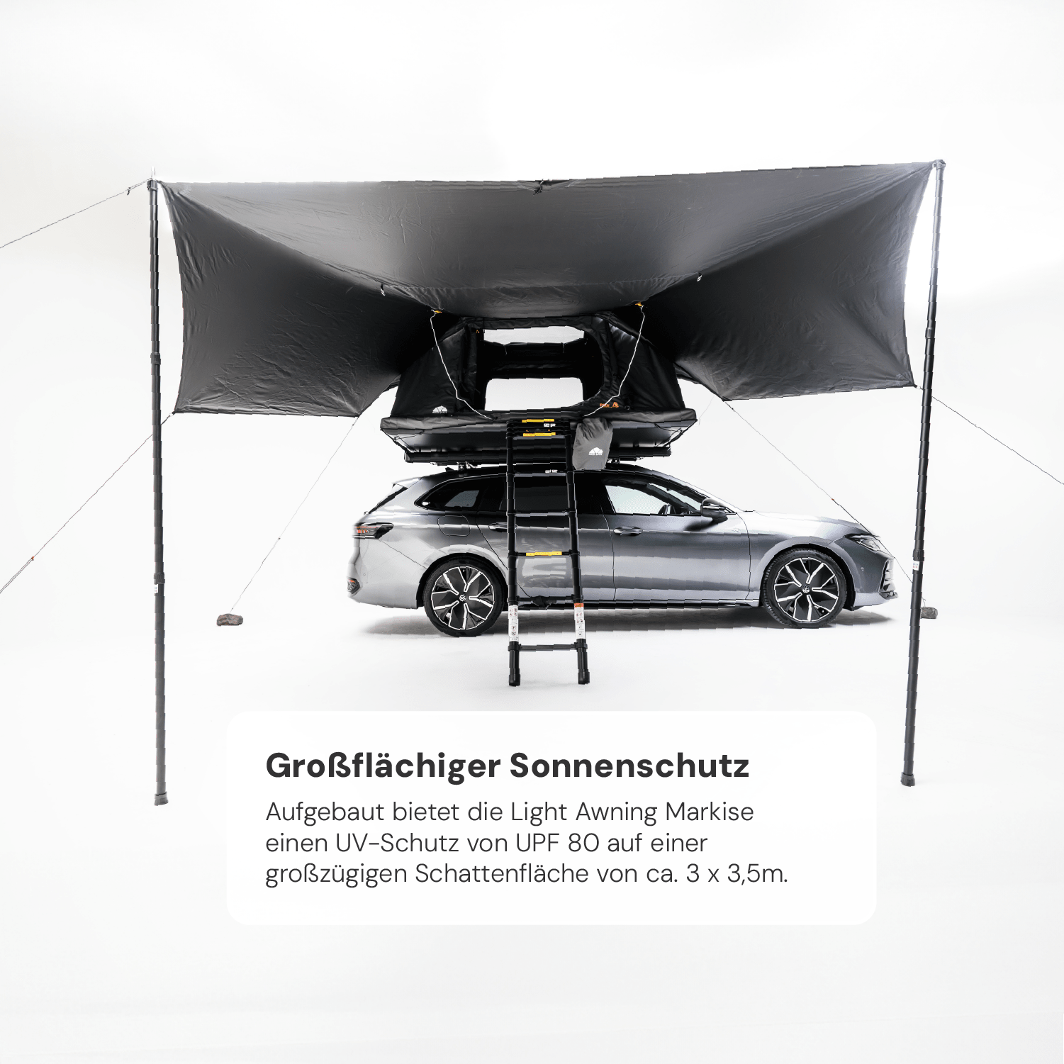 Graues Auto mit Dachzelt und großflächiger, schwarzer Markise im Studio. Text im Vordergrund: "Großflächiger Sonnenschutz. UV-Schutz UPF 80. ca. 3 x 3,5m."