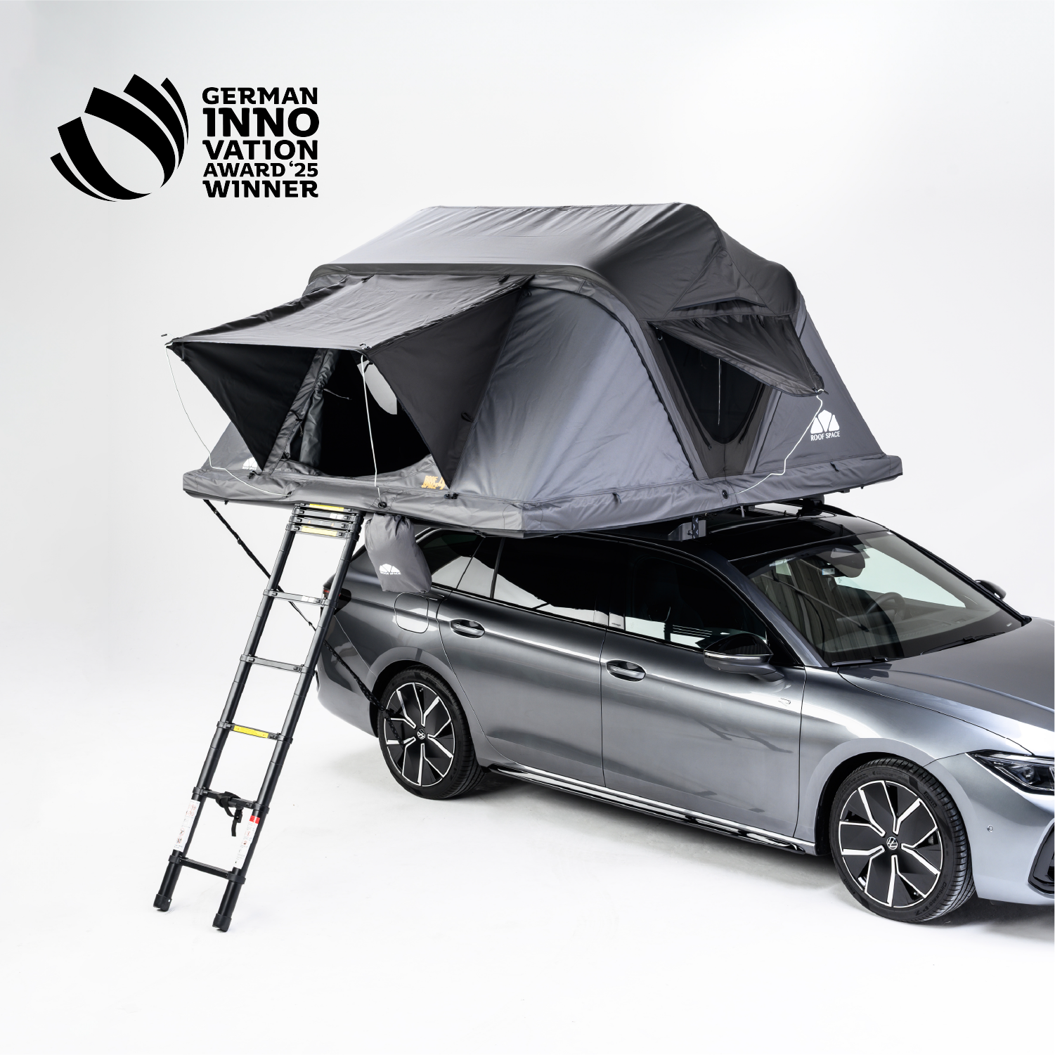 Graues Auto mit Dachzelt und Leiter vor hellem Hintergrund. Text oben links: "GERMAN INNOVATION AWARD '25 WINNER".