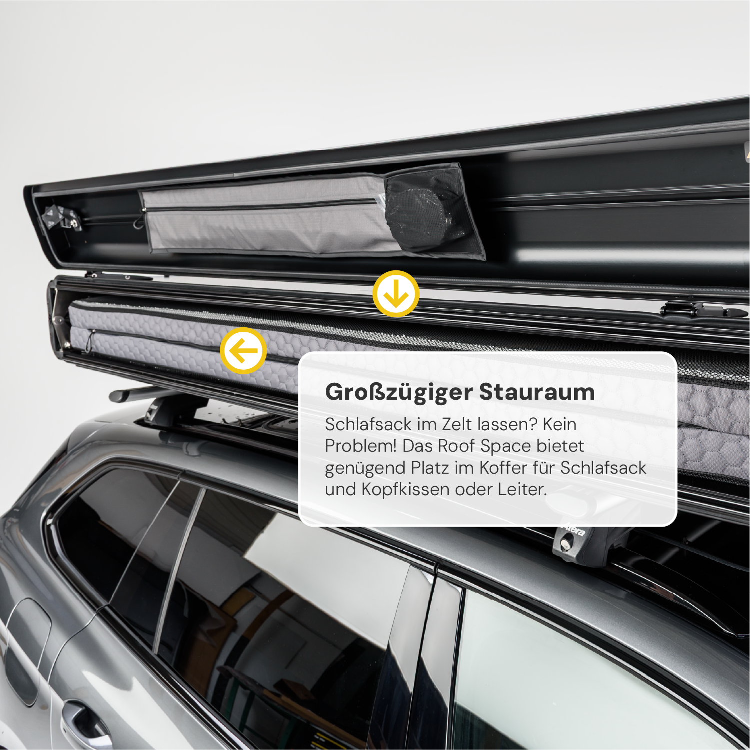 Dachbox auf einem grauen Auto mit Hinweispfeilen und Text "Großzügiger Stauraum", der auf das geräumige Innere hinweist.
