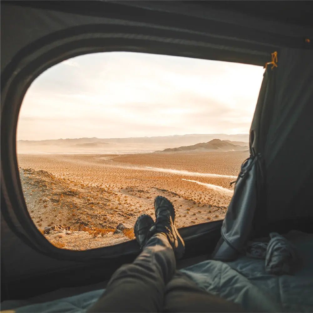 View from inside the open rooftop tent Roof Space 4 looking out over a vast, barren landscape.