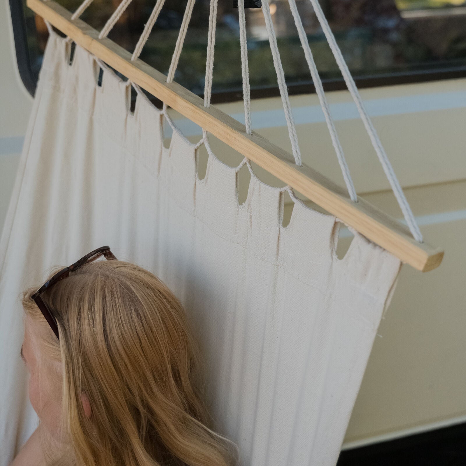Detailaufnahme: Frau liegt mit Sonnenbrille auf dem Kopf in der Roof Space Hängematte, welche am Dachzelt befestigt ist.