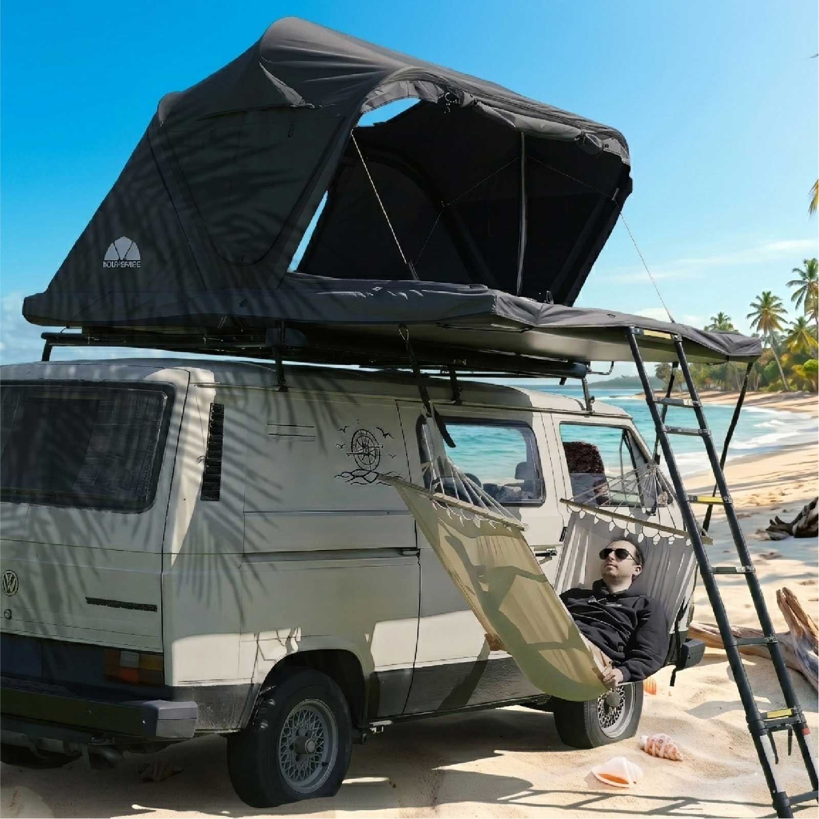 Eine Person entspannt sich in einer Hängematte, die sicher unter dem am Strand aufgebauten Roof Space Dachzelt befestigt ist.