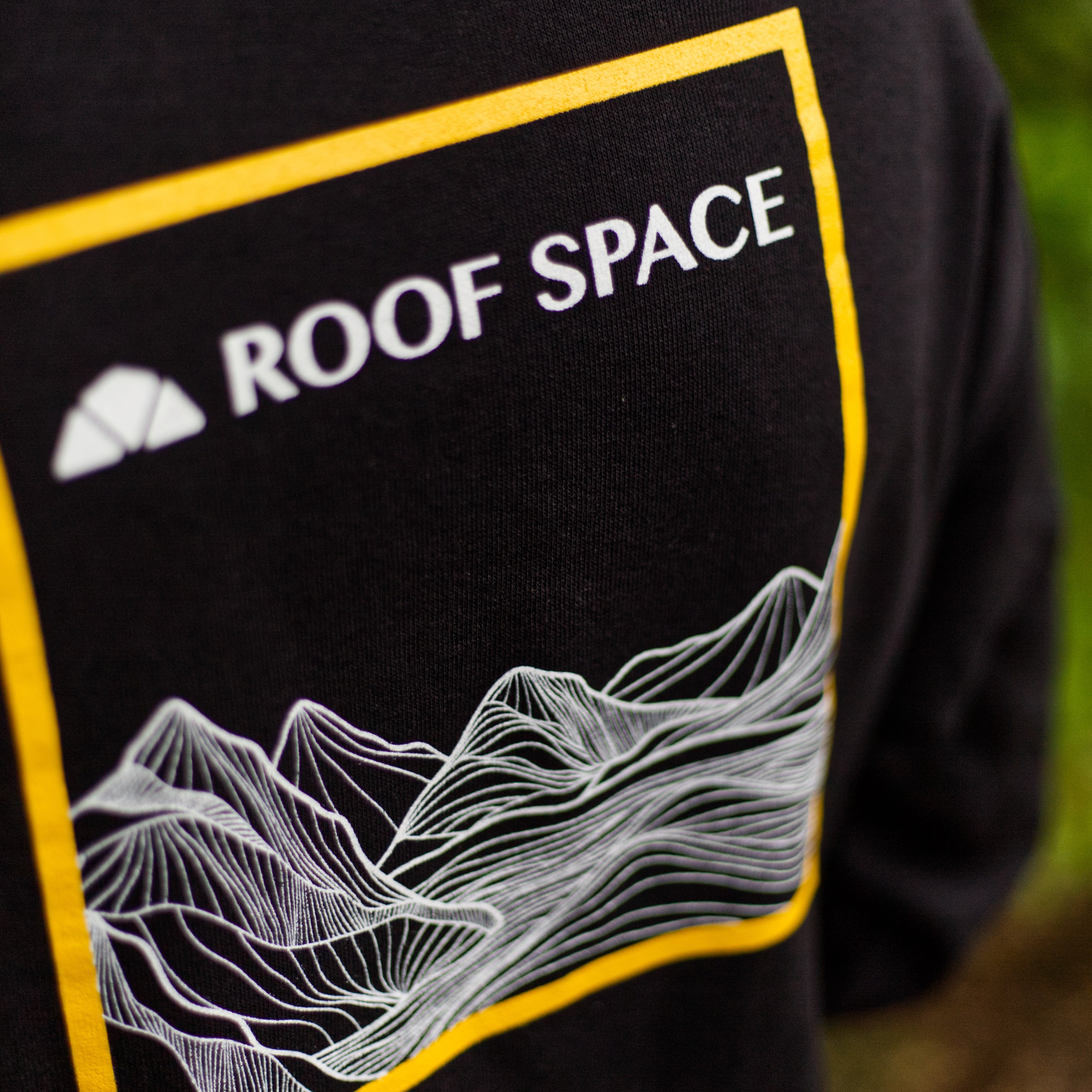Schwarzes Langarmshirt mit weiß-gelbem Roof Space Logo und Berglinien