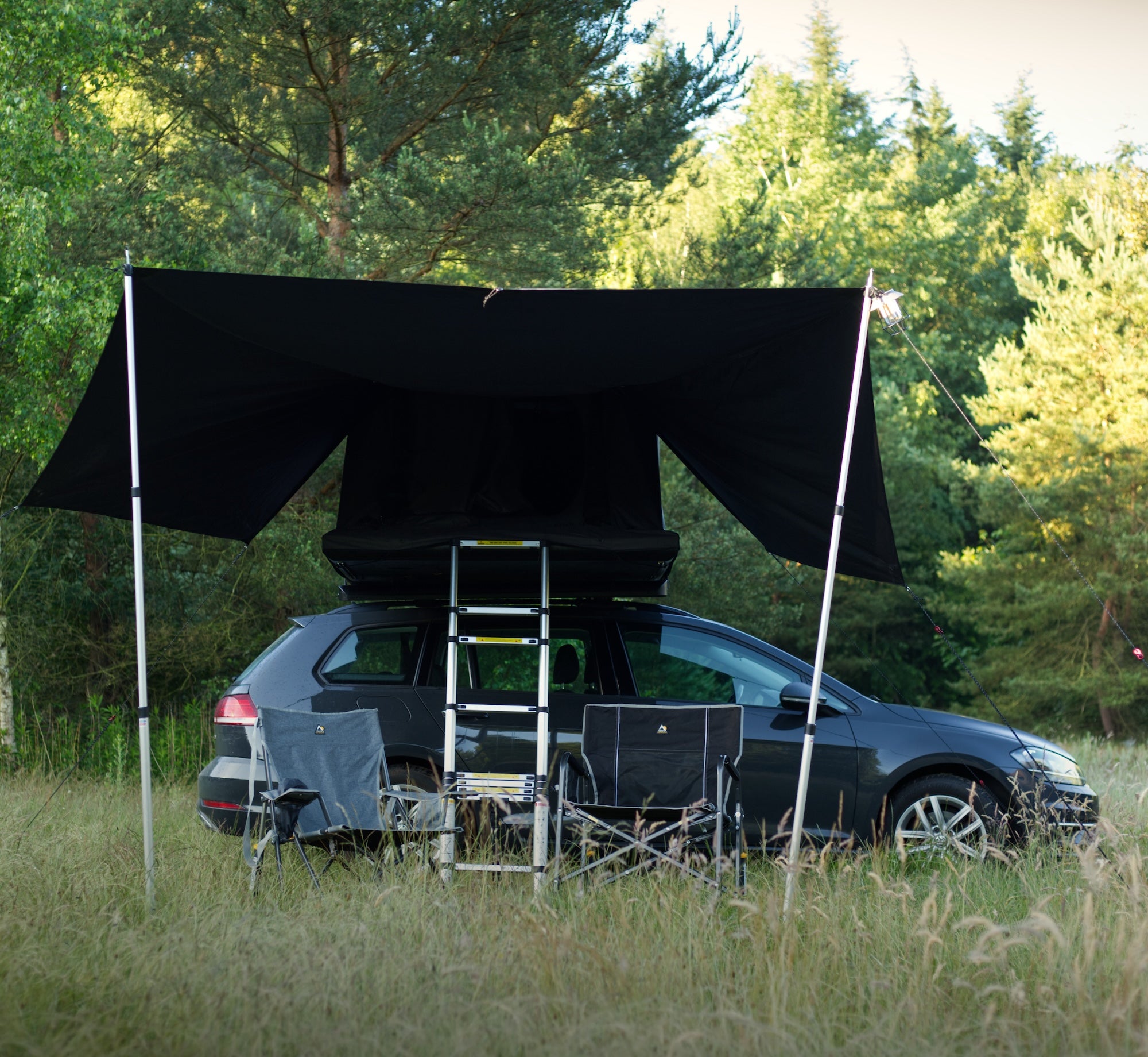 Schwarzes Stoffverdeck mit silbernen Stangen über Auto im Grasfeld – Light Awning