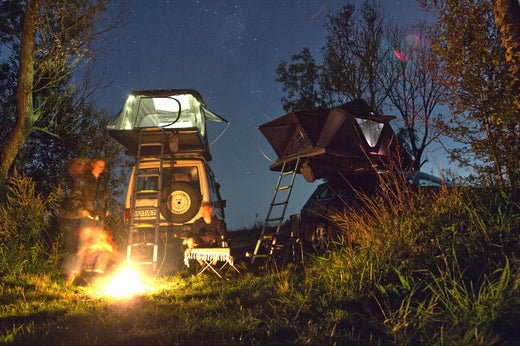 Nächtliches Camping-Idyll: Zwei Autos mit Dachzelten unter Sternen, Lagerfeuer und gemütlicher Atmosphäre. Abenteuerurlaub mit dem eigenen Auto.
