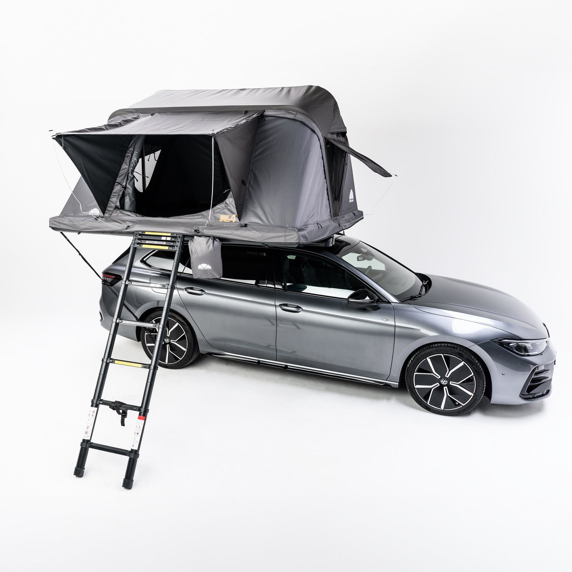 Graues Auto mit grauem Dachzelt und Leiter auf weißem Hintergrund. Das Zelt ist teilweise geöffnet. Text "ROOF SPACE 4" sichtbar.