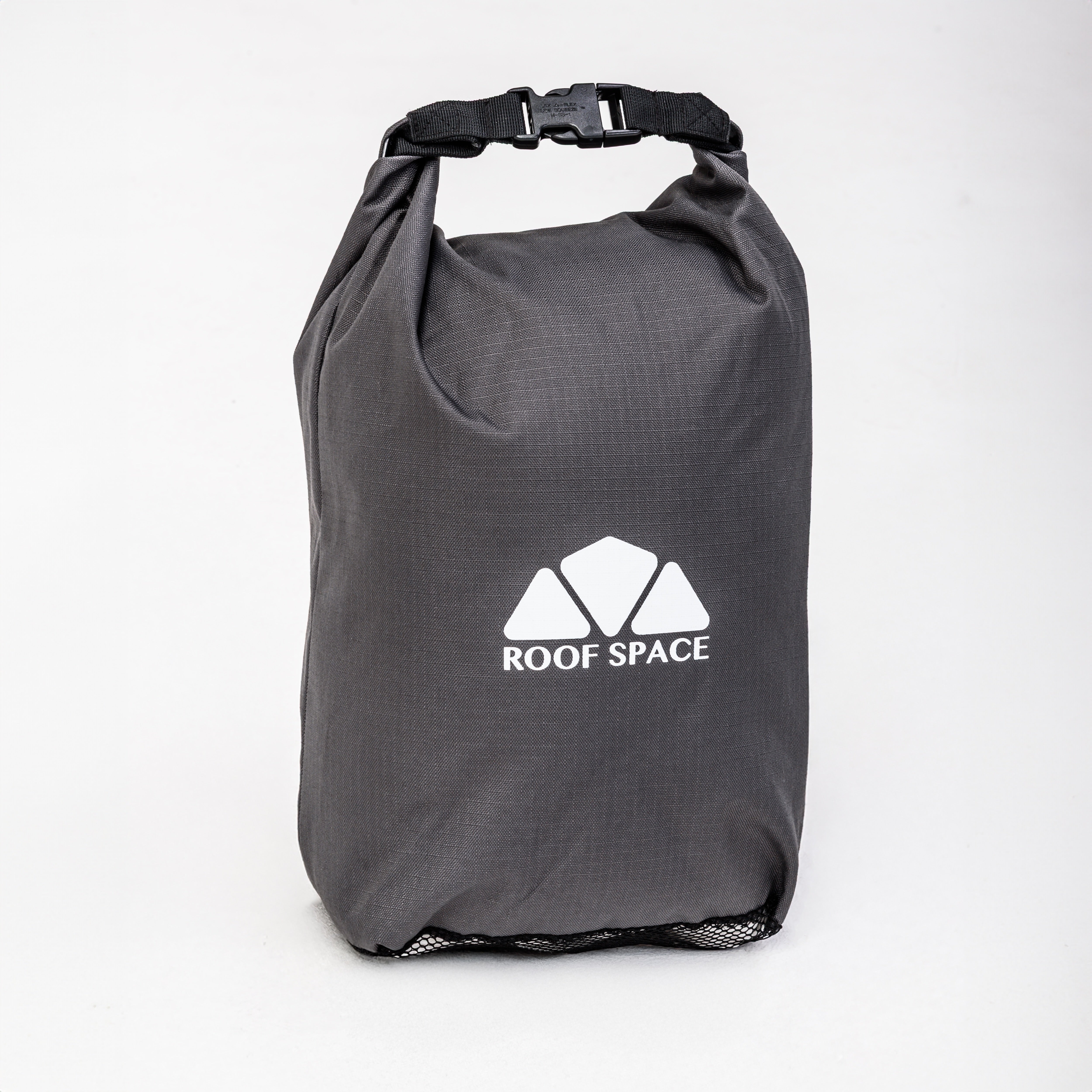 Ein grauer Packsack mit dem Logo "ROOF SPACE" steht mittig vor einem weißen Hintergrund. Der Sack ist oben mit einem schwarzen Gurt verschlossen.