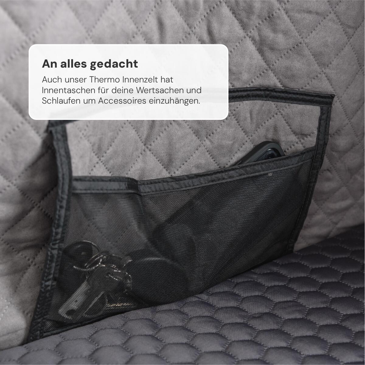 Nahaufnahme eines grauen Innenzelts mit schwarzer Netztasche, gefüllt mit Schlüsseln und einem Handy. Text: "An alles gedacht... Accessoires einzuhängen."