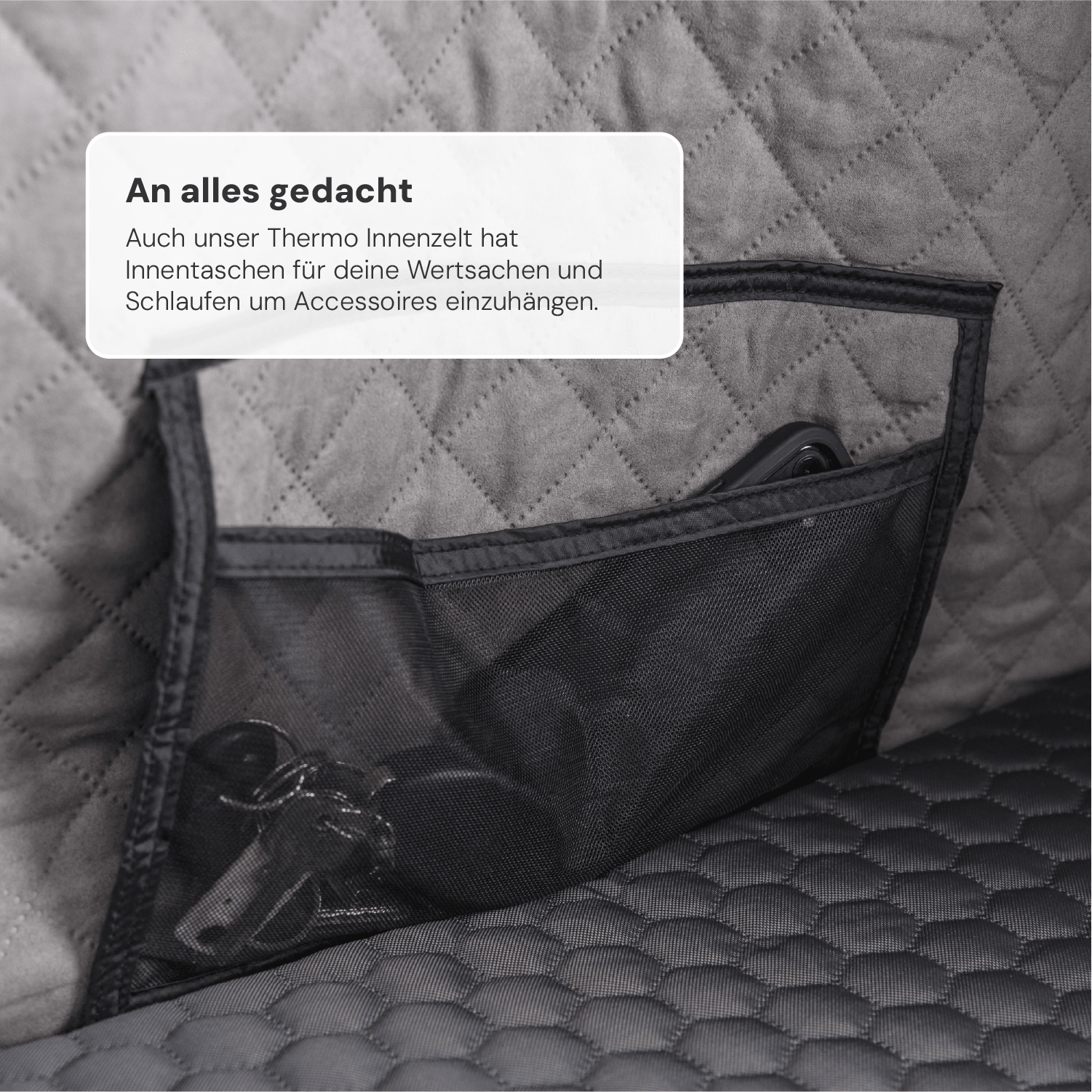 Nahaufnahme eines grauen Innenzelts mit schwarzer Netztasche, gefüllt mit Schlüsseln und einem Handy. Text: "An alles gedacht... Accessoires einzuhängen."