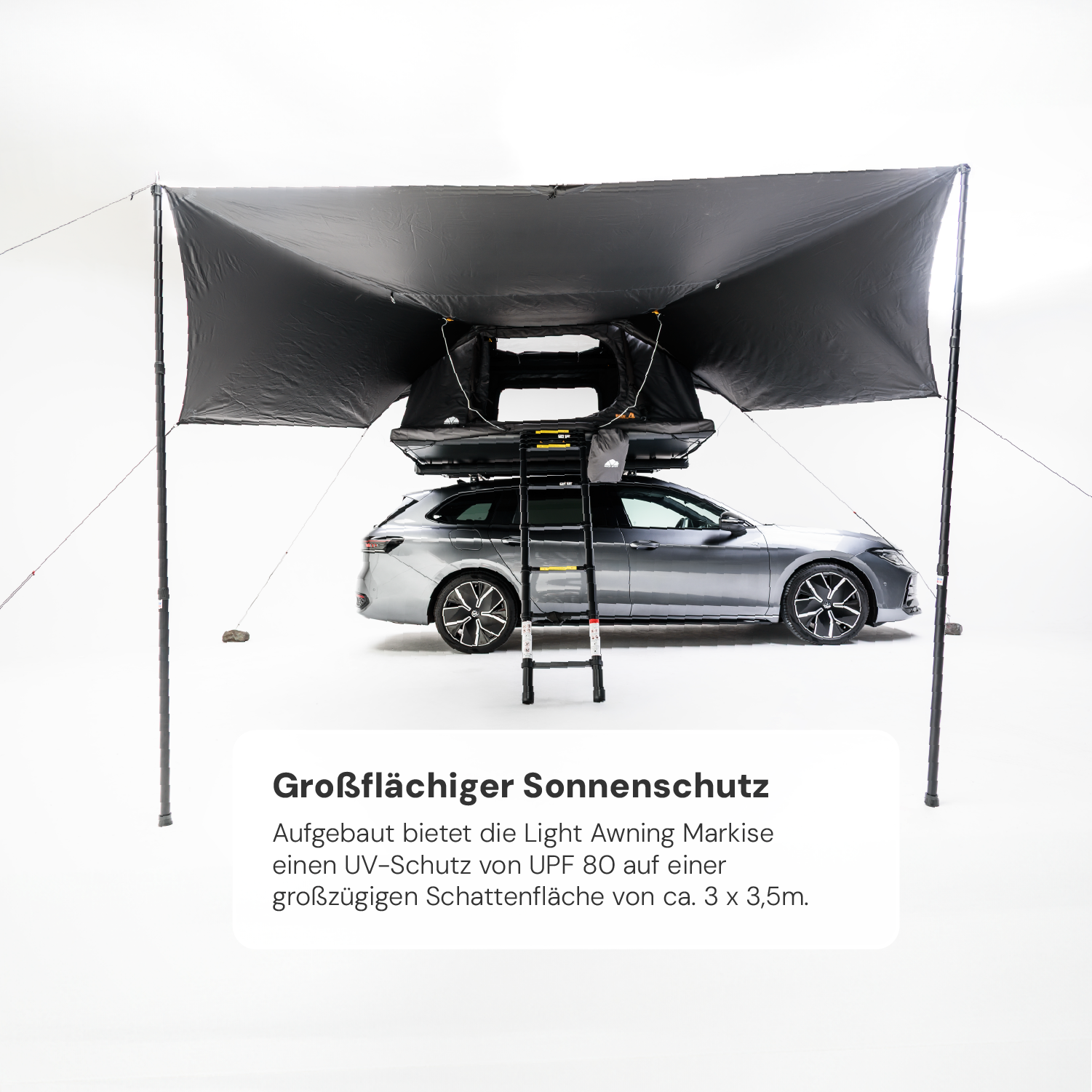 Graues Auto mit Dachzelt und großflächiger, schwarzer Markise im Studio. Text im Vordergrund: "Großflächiger Sonnenschutz. UV-Schutz UPF 80. ca. 3 x 3,5m."
