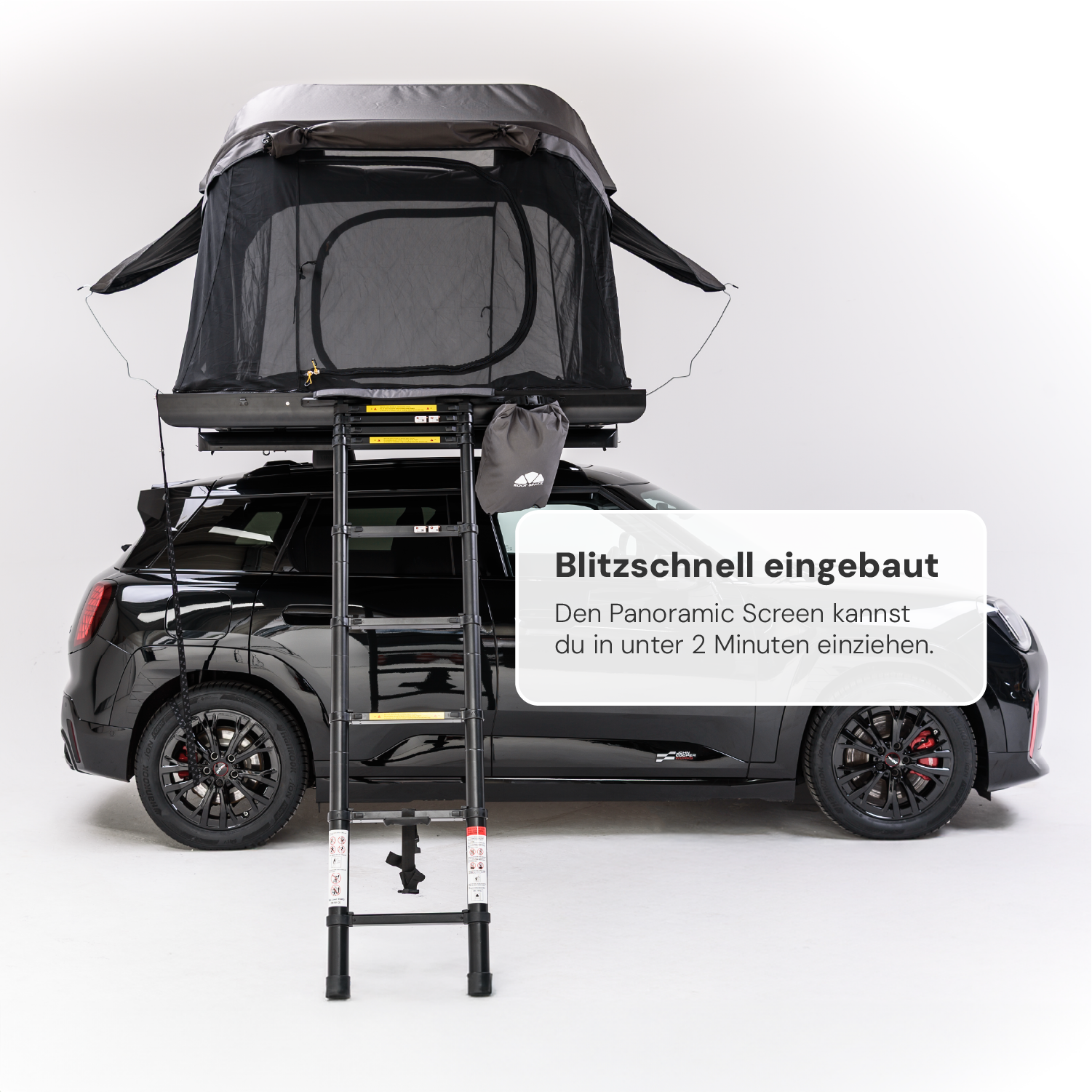 Schwarzer Mini Cooper mit aufgesetztem Dachzelt und ausziehbarer Leiter vor weißem Hintergrund. Text: "Blitzschnell eingebaut. Den Panoramic Screen kannst du in unter 2 Minuten einziehen."