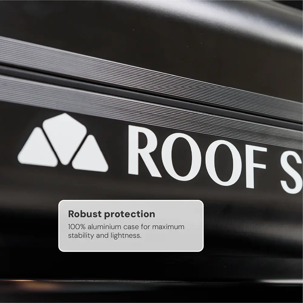 Close-up of a black roof box with the white logo "ROOF S" and the text "Rugged protection. 100% aluminum case".