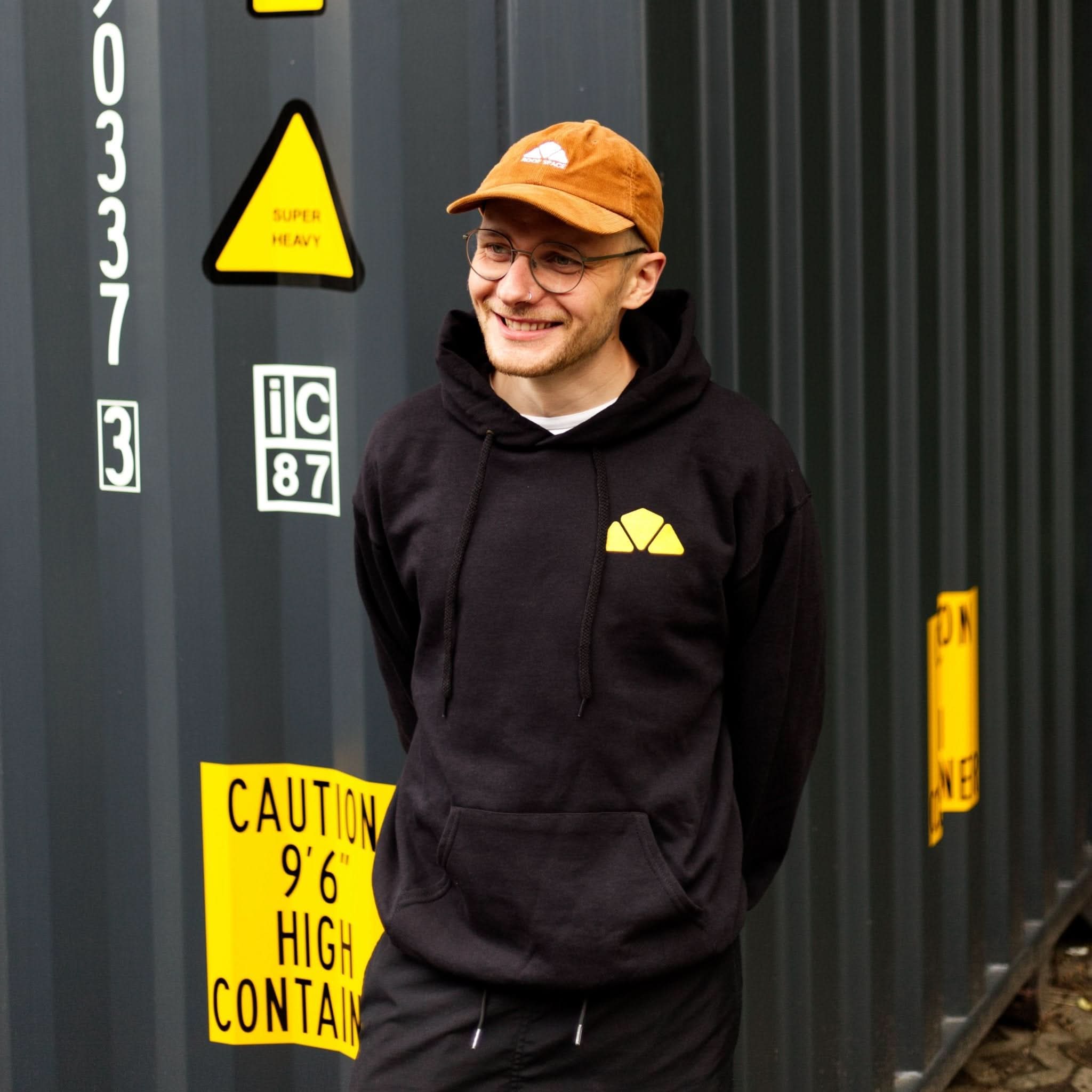 Schwarzer Hoodie mit gelbem dreieckigem Logo auf der Brust