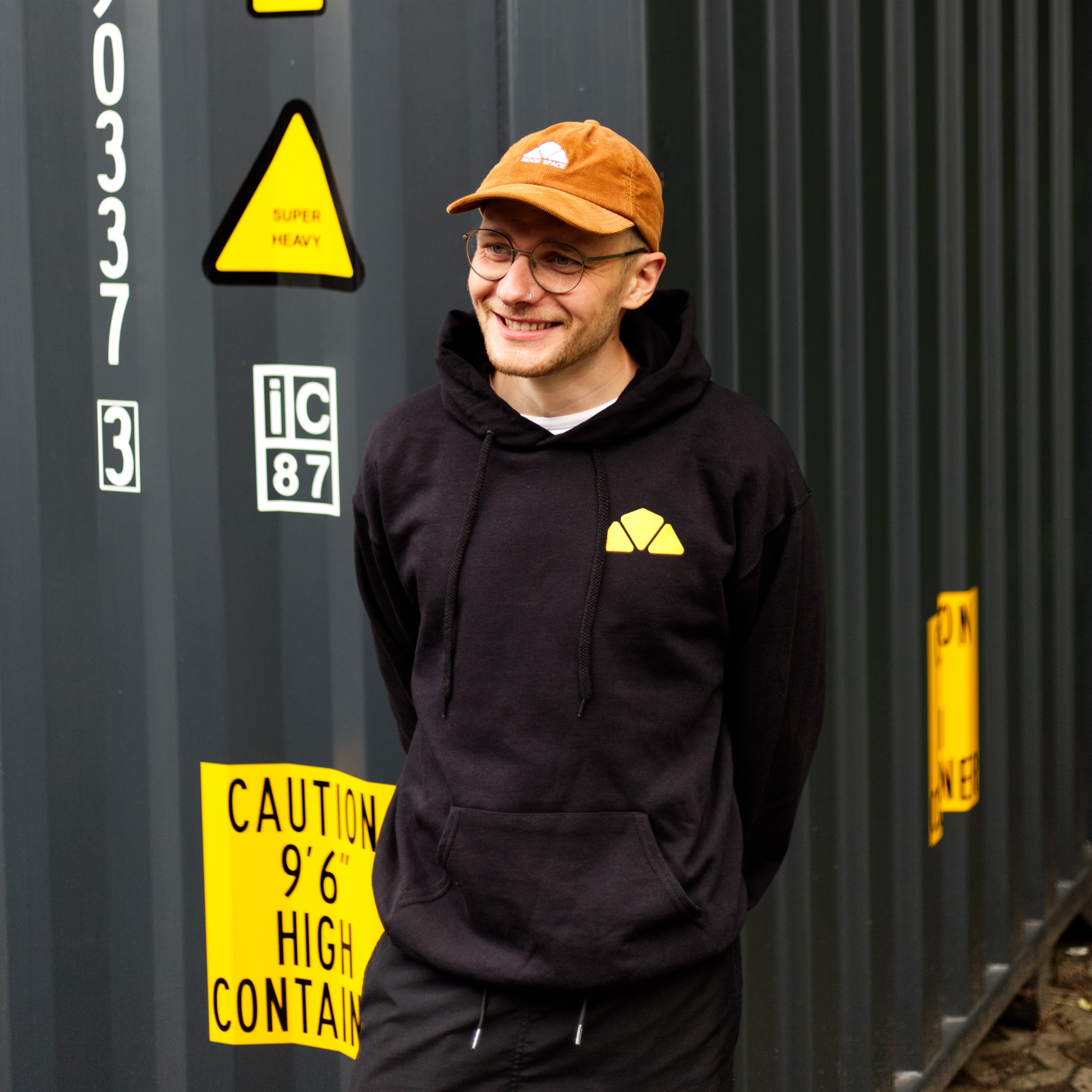 Schwarzer Hoodie mit gelbem dreieckigem Logo auf der Brust