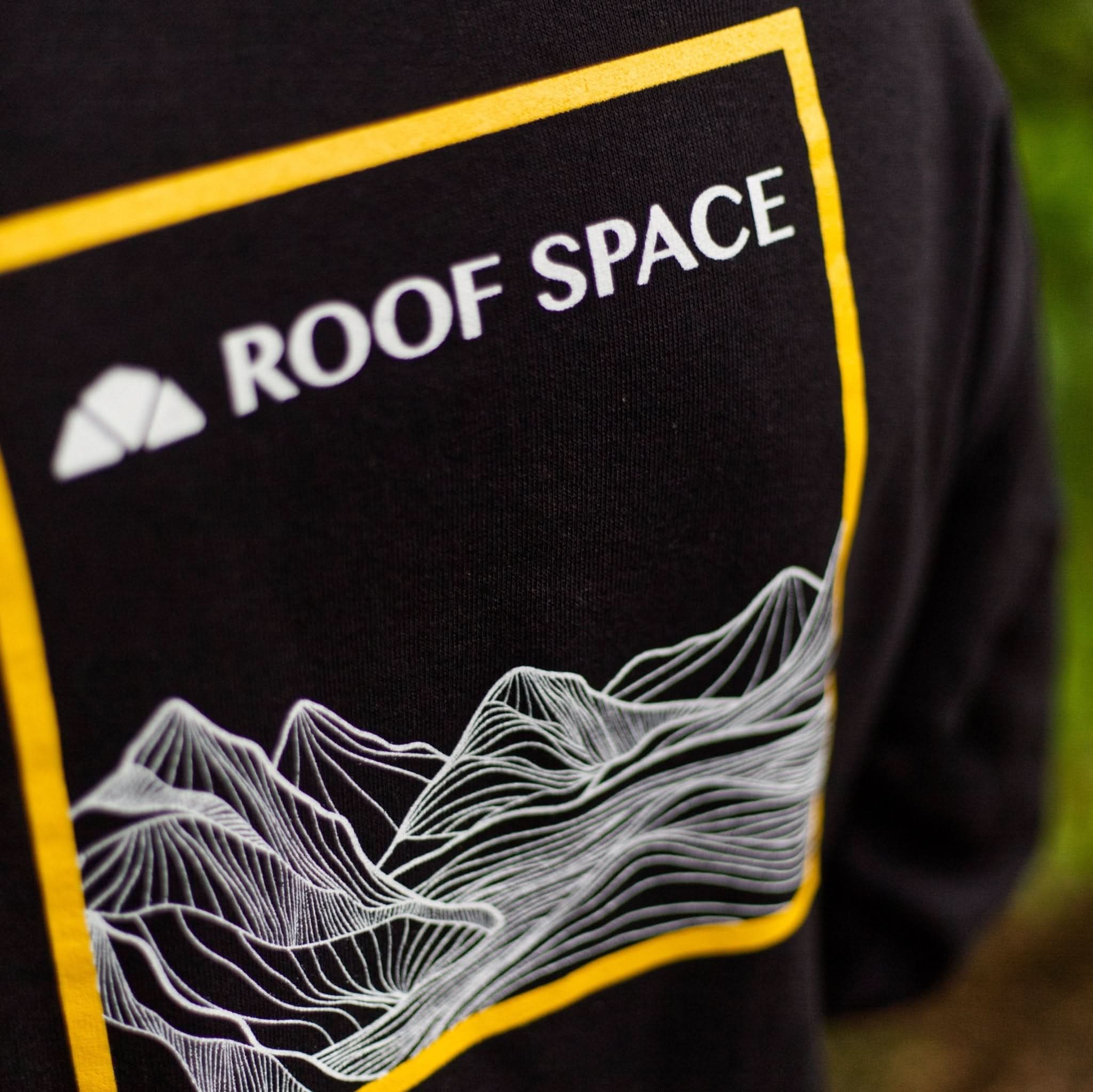 Schwarzes Langarmshirt mit weiß-gelbem Roof Space Logo und Berglinien